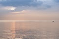 Sunrise over ocean showing silhouetted fishing boats and water reflecting golden colors and textures