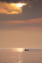 Sunrise over ocean showing silhouetted fishing boats and water reflecting golden colors and textures