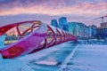 Sunrise over Peace Bridge in Calgary with frozen ice and snow-covered Bow River in Winter