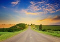 Sunrise over picturesque landscape. Straight road and fields