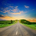 Sunrise over picturesque landscape. Straight road and fields