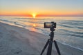 Sunrise over the sea coast. Fireball of the sun above the horizon in a colorful orange sky. Smartphone camera on a tripod in Royalty Free Stock Photo