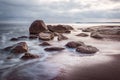 Sunrise over the sea rocks on the beach. Smooth waters, long exposure effect. Seascape in beautiful blue and purple colors.