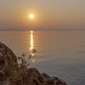 Sunrise over the sea and the silhouette of a flower in its rays. Corfu island, Greece. Background. Space for text Royalty Free Stock Photo