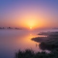 Sunrise over a serene lake with gentle mist floating above the water. Royalty Free Stock Photo