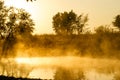 Sunrise over a small farm lake with mist rising off the water.