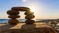 Sunrise over a small pebble tower on the beach.