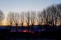 Sunrise over small town. Fiery dawn in the dark sky, horizontal photo. Silhouettes of trees, cars and industrial buildings