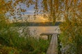 Sunrise over wooden pier on the lake. Wooden footbridge on the lake in the sunrise. A beautiful sunrise over lake greets the morni