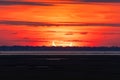 Sunrise during a partial solar eclipse, with a crescent shaped sun on the horizon over water.