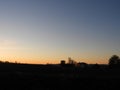 Sunrise peaks from behind a hill with pole barn silhouette