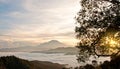 Sunrise peeking from behind a tree with mountain and sea of cloud as background.