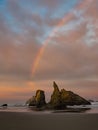 Sunrise and rainbow on ocean beach with cliffs