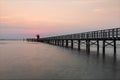 Sunrise at the red lighthouse of Lignano, landscape on the sea with a pedestrian promenade.