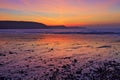 Sunrise reflected in the wet sand and pebbles of Freshwater East beach Royalty Free Stock Photo