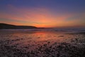Sunrise reflected in the wet sand and pebbles of Freshwater East beach Royalty Free Stock Photo