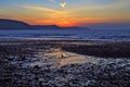 Sunrise reflected in the wet sand and pebbles of Freshwater East beach Royalty Free Stock Photo