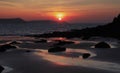 Sunrise reflected in the wet sand and rocks of Freshwater East beach