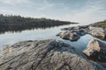 Sunrise on a rocky shore. Still water. Pine forest in the background