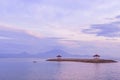 Sunrise on Sanur beach in Bali. Agung volcano in the dawn rays of the pink sun. Traditional gazebos on an artificial Royalty Free Stock Photo