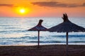 Sunrise on the sea and reed umbrellas on the beach