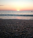 Sunrise seen from a beach rushed by sea waves