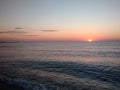 Sunrise seen from a beach rushed by sea waves