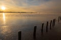 A sunrise seen from the shore of a lake during winter time. The rising sun reflects in the thin layer of ice on the water between Royalty Free Stock Photo