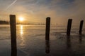 A sunrise seen from the shore of a lake during winter time. The rising sun reflects in the thin layer of ice on the water between Royalty Free Stock Photo