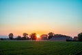 Sunrise Serenity: Rural Countryside with Golden Sun Peeking Through Trees Royalty Free Stock Photo