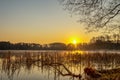 A sunrise on a small lake with fog and golden warm light.