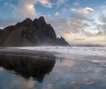 Sunrise Stokksnes cape sea beach and Vestrahorn Mountain with its reflection on wet black volcanic sand surface, Iceland. Amazing