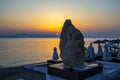 Sunrise and stone carving relief of a human and a snake in Pefkohori