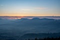 Sunrise sun hidden behind cloud in mountains with fog in valley Royalty Free Stock Photo