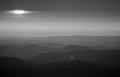 Sunrise sun peeks through the clouds over mountain range Royalty Free Stock Photo