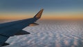 Sunrise or sunset flight with airplane wing and view of earth