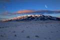 Sunrise or Sunset Sunlight Sun Light on Snow Covered Mountains with Crescent Moon