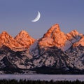Sunrise on Teton Mountain Range in Wyoming Alpen Glow Orange and Pink on Rugged Mountains with Crescent Moon Royalty Free Stock Photo