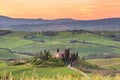 Sunrise in Tuscany with a rolling landscape and a farm on the hill Royalty Free Stock Photo