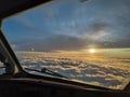 the sunrise is visible over clouds from an airplane window, as seen from the cockpit Royalty Free Stock Photo