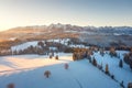 Sunrise in winter mountains. Scenic nature of snowy summits of mountain range illuminated by sun. Aerial view of mountains in
