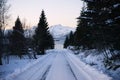 Sunrise, winter, unfrozen water, snow-capped mountains and snowy road