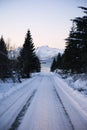 Sunrise, winter, unfrozen water, snow-capped mountains and snowy road