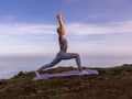 Sunrise yoga. Young slim woman practicing Virabhadrasana I, Warrior I Pose. Strong fit body. Yoga retreat. Healthcare concept.