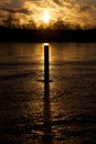 Sunrise over frozen lake with a pole in the ice casting long shadow