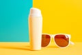 Sunscreen bottle with sunglasses on yellow and blue background. Sun protection concept