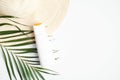 Sunscreen cream bottle on white background with female beach hat and tropical palm leaf. Flat lay, top view, copy space. Summer Royalty Free Stock Photo