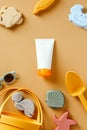 Sunscreen cream tube for babies and beach toys on yellow background. Flat lay, top view Royalty Free Stock Photo