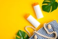 Sunscreen lotion bottles, green tropical leaves, female striped beach bag on yellow background. Sun protection, suntan cosmetic Royalty Free Stock Photo