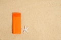 Sunscreen in orange plastic tube with white starfish on sand background . Sunscreen with UVA and UVB protection. Summer, sea